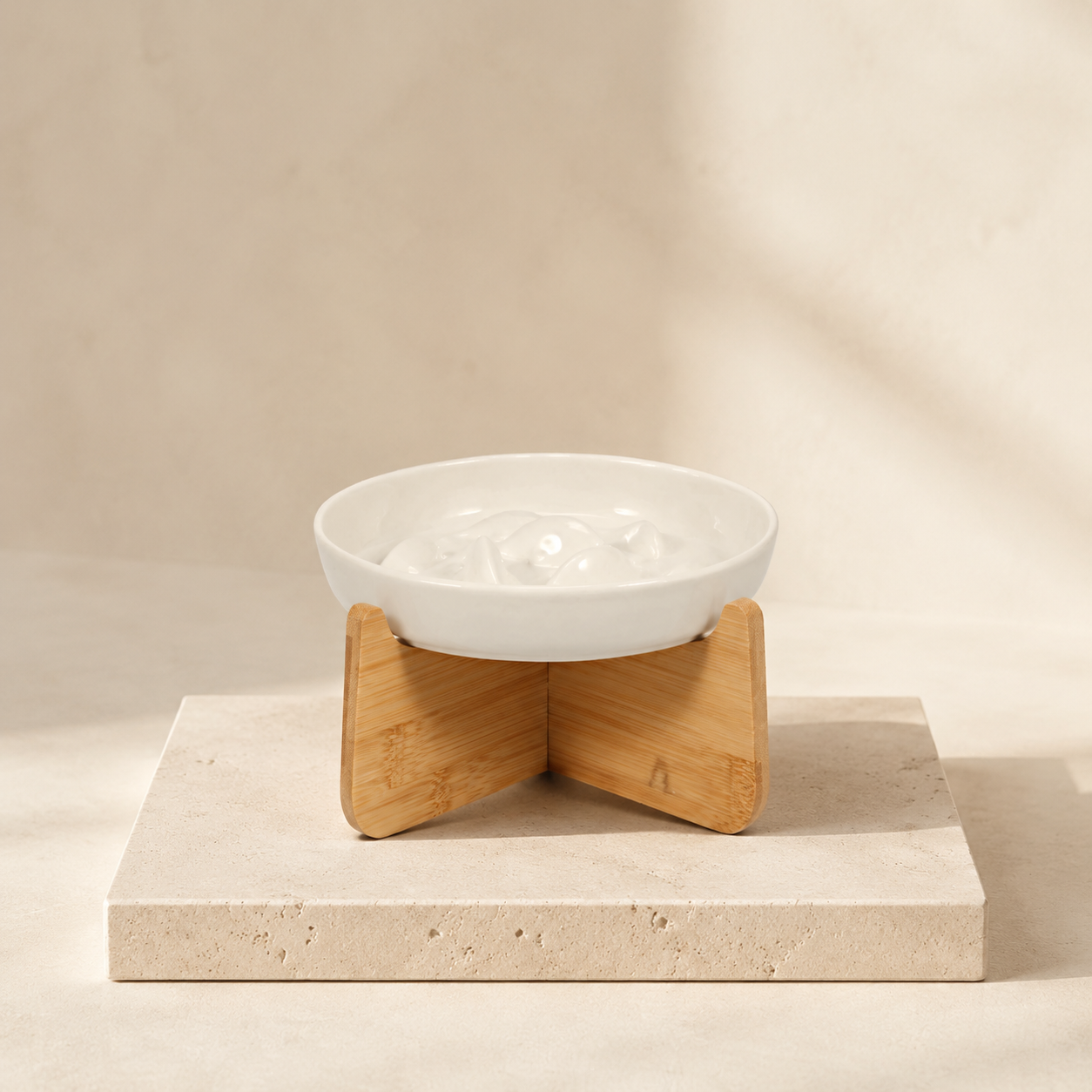 Arlo ceramic slow feeder bowl on a wooden stand on travertine